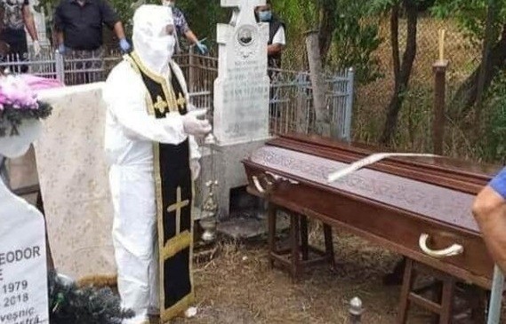 Preot din România surprins echipat în combinezon anti-COVID la o înmormântare